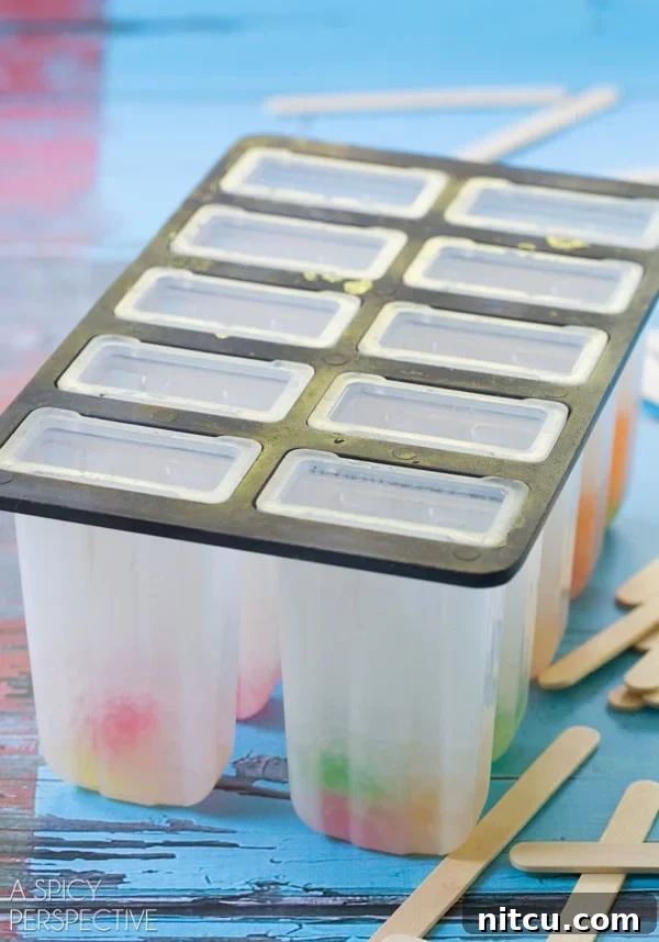 Step-by-Step Alcoholic Popsicle Making Popsicle molds with the first layer of vodka gummy bears and soda