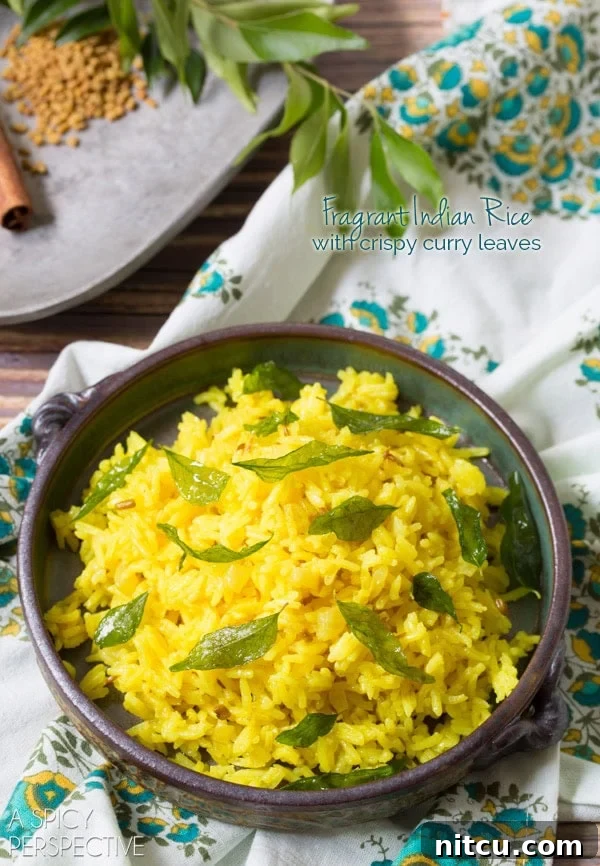A vibrant bowl of fragrant Indian Turmeric Rice, beautifully garnished with fresh, green curry leaves, ready to be served.