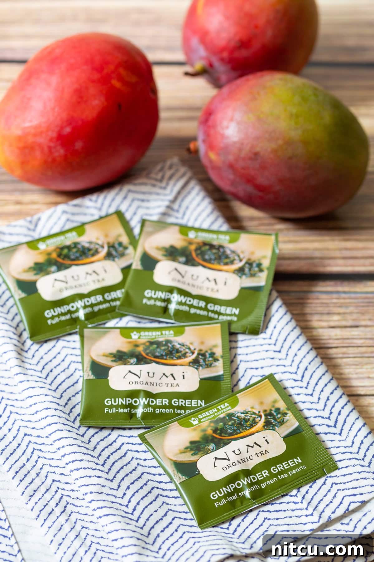 Vibrant Mango Green Tea Refresher 3 Several green tea bags arranged neatly on a white and blue patterned towel, highlighting the primary energy-boosting ingredient for the smoothie.