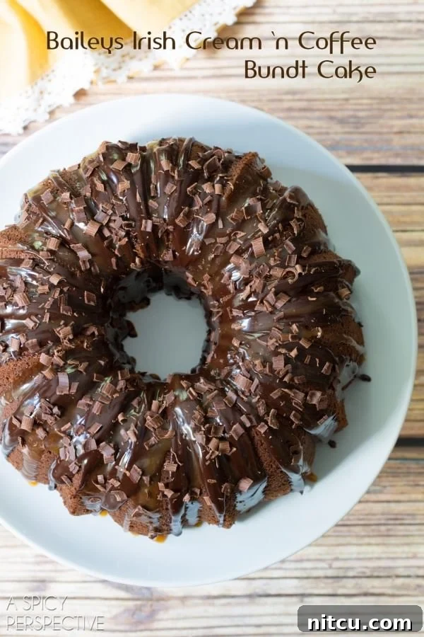 Irish Cream Dream Bundt 2 A beautifully decorated Baileys Irish Cream Bundt Cake, glistening with chocolate ganache and caramel drizzle, presented on a elegant white platter.