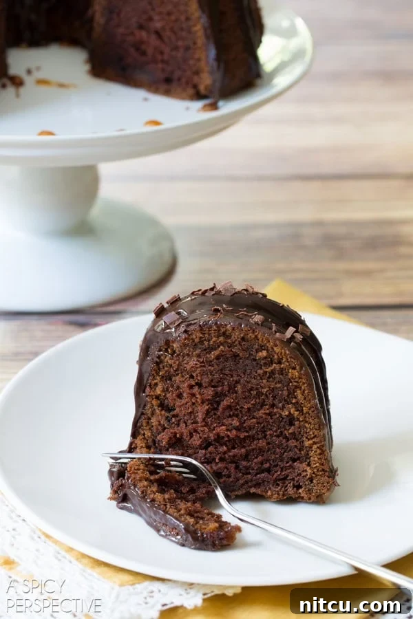 Irish Cream Dream Bundt 11 A delicious slice of Baileys Irish Cream Bundt Cake, beautifully presented on a plate with a fork, showing off its perfect texture and rich toppings.