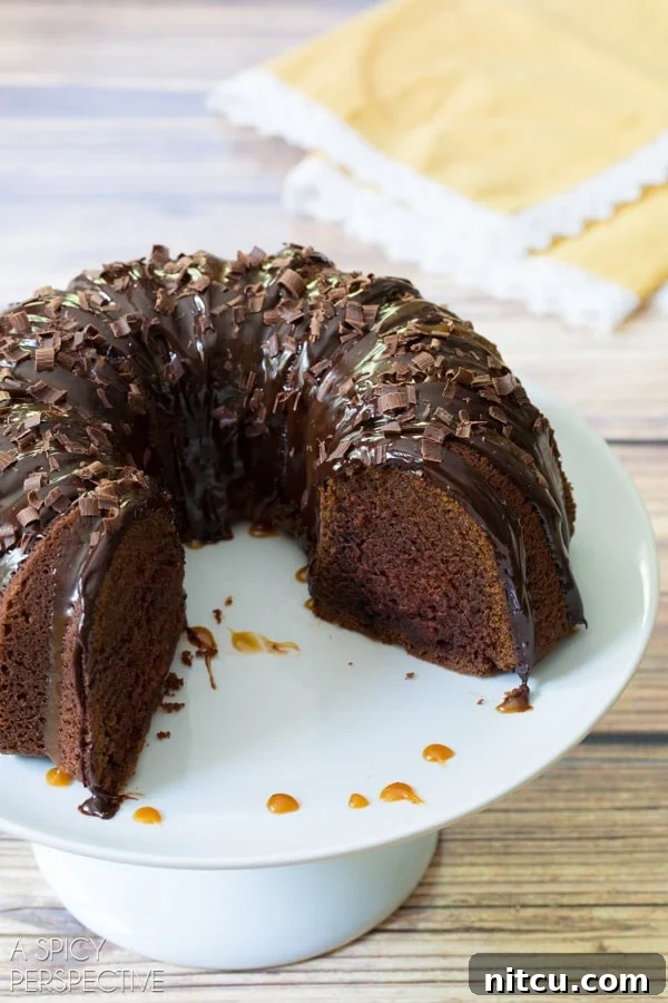 Irish Cream Dream Bundt 4 A plated slice of Baileys Irish Cream Bundt Cake, showcasing its moist interior and generous toppings, with a piece already enjoyed.