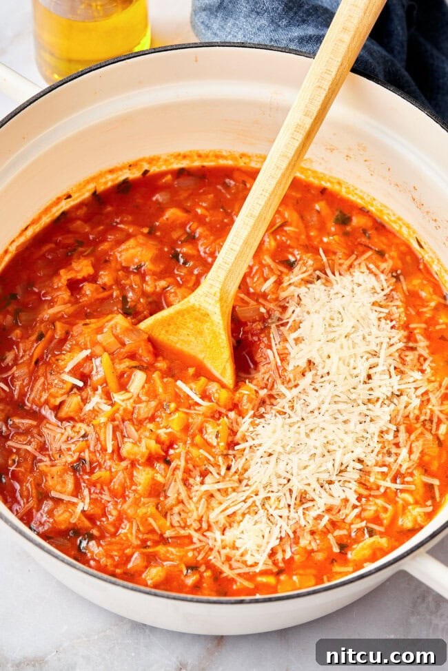 Rustic Italian Tomato Bread Soup Pappa al Pomodoro 9 A pot of Pappa al Pomodoro simmering, with Parmesan cheese being added and stirred in.