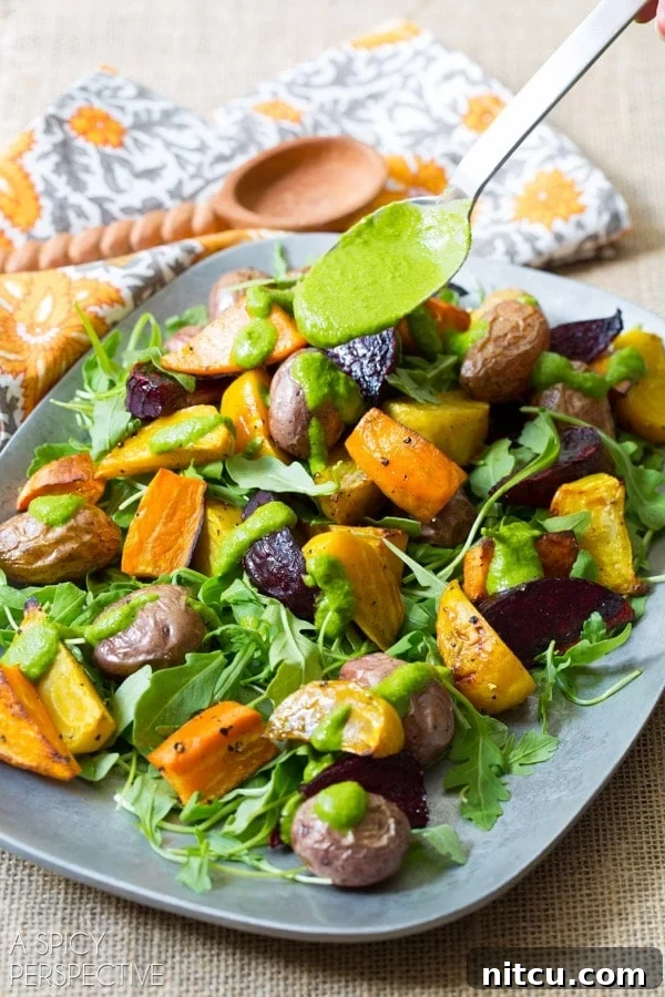 Golden Roasted Root Medley 6 A hand drizzling homemade cilantro dressing over the roasted root salad on a serving platter.