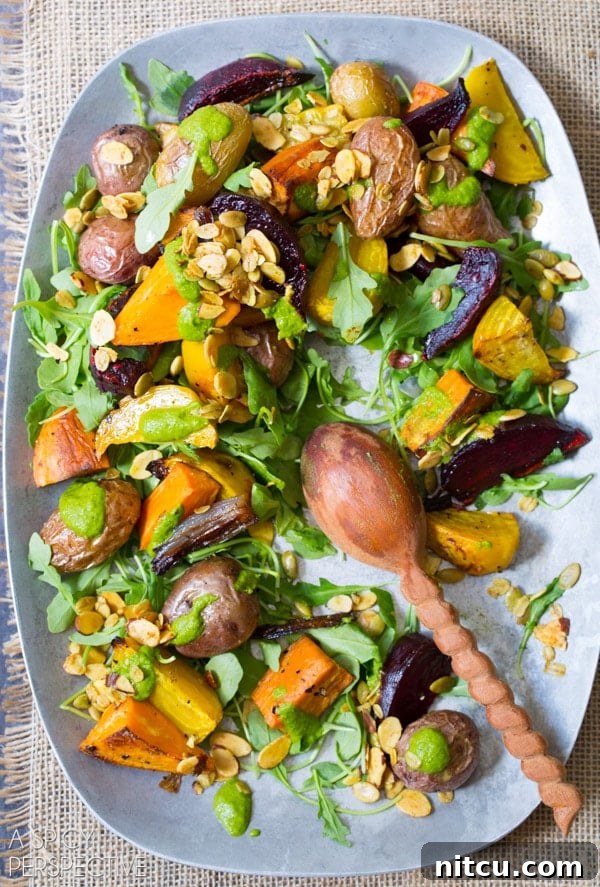 Golden Roasted Root Medley 7 A top down view of roasted vegetable salad on a serving platter. A wooden spoon is resting on the platter where a few servings of the salad are missing.