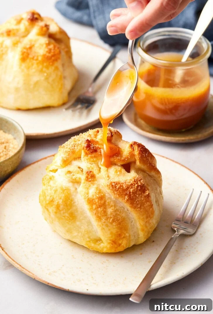 Flaky Apple Pastry Pockets 12 Finished mini apple pie bomb on a plate with caramel being drizzled on top with a spoon.