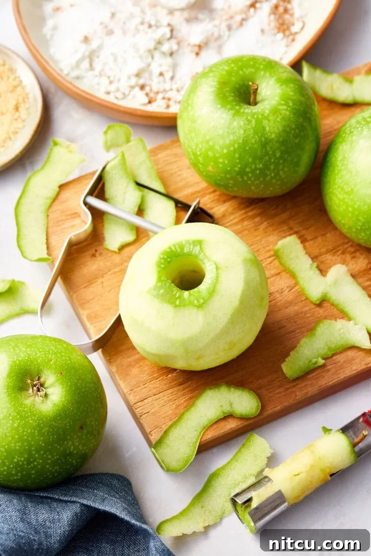 Flaky Apple Pastry Pockets 6 Green apples on a wooden cutting board being peeled.