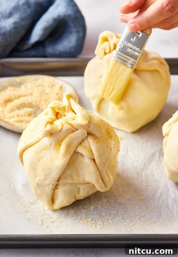 Flaky Apple Pastry Pockets 10 Un-baked puff pastry mini apple pie bombs with pastry brush brushing egg wash.