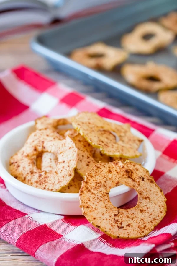 Golden Apple Crisps 6 Baked apple chips in a white bowl on a red and white linen.