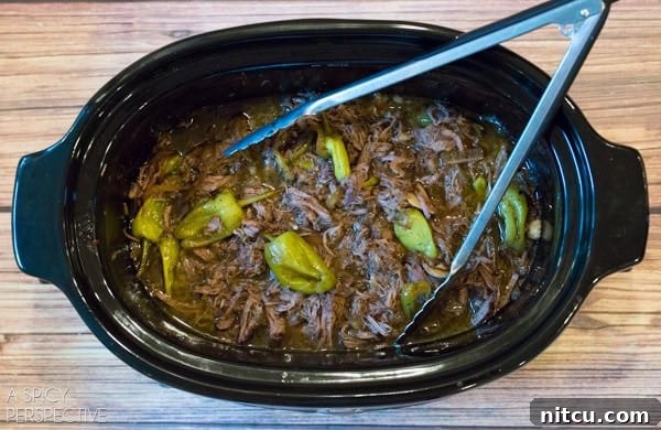 Perfect Slow Cooker Italian Beef 5 Italian Beef cooking in a slow cooker, showing tender meat in savory broth