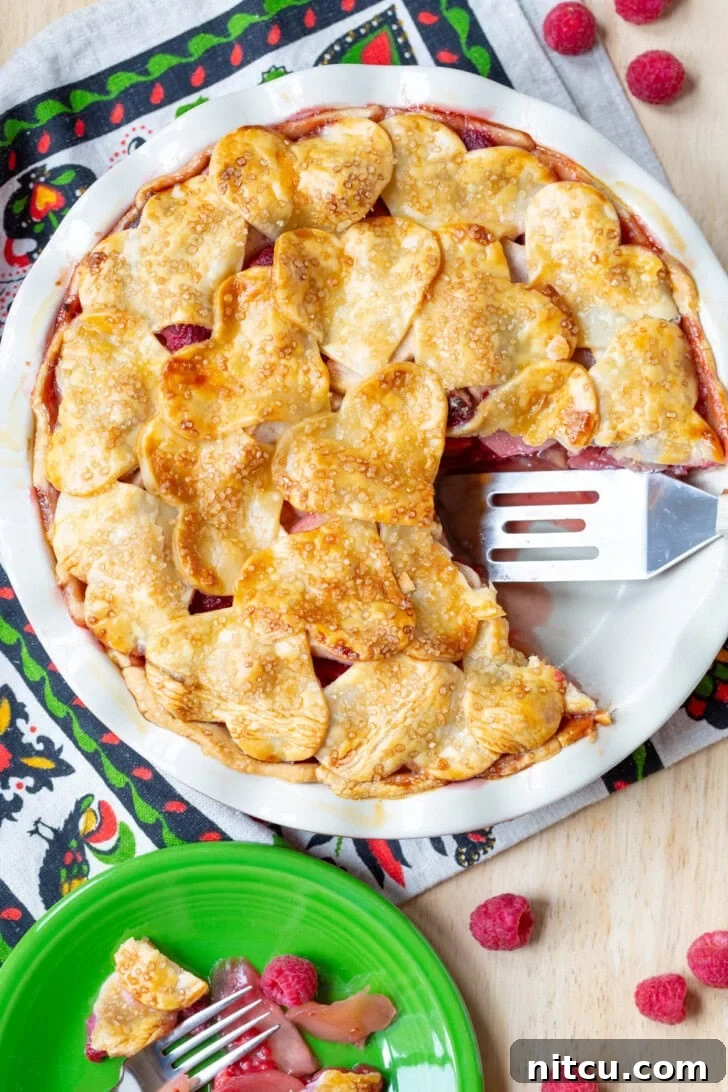 Berry Kissed Apple Pie 2 Delectable Raspberry Apple Pie with a slice removed, showcasing the vibrant fruit filling.