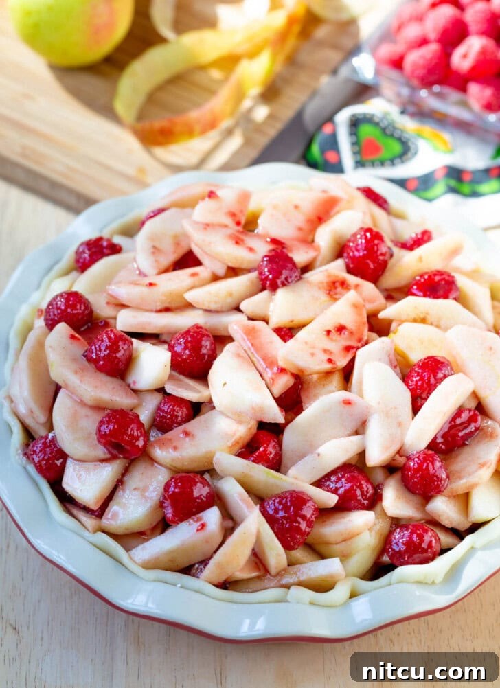 Berry Kissed Apple Pie 5 Unbaked Raspberry Apple Pie filling already nestled in a pie crust, ready for the top layer.