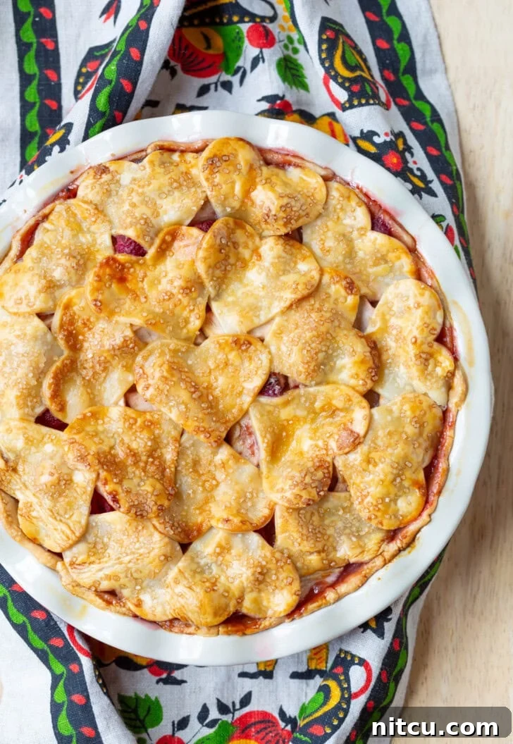 Berry Kissed Apple Pie 7 A whole Raspberry Apple Pie, perfectly baked with a golden crust and intricate top design, ready to be served.
