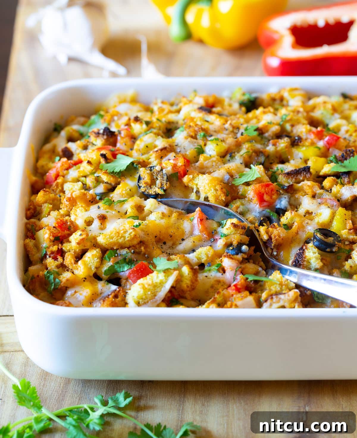 Southwest Cornbread Stuffing with Chiles Cornbread Stuffing Recipe - Mexican Thanksgiving version with vibrant chiles and melted cheese in a baking dish, served with a spoon