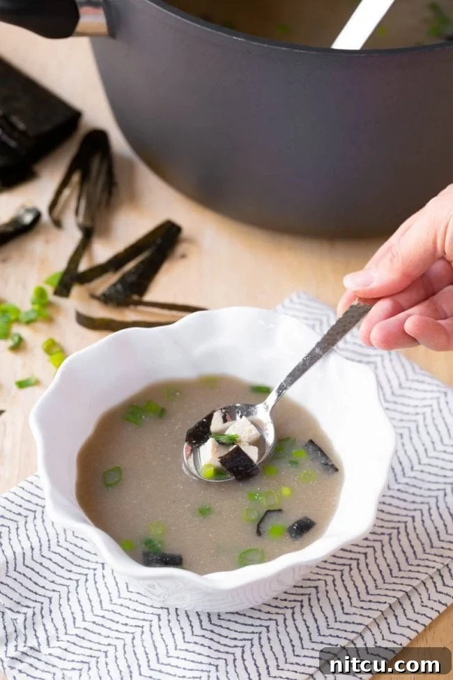 miso-soup Side view of a pot and bowl filled with homemade Japanese Miso Soup, accompanied by a wooden spoon.