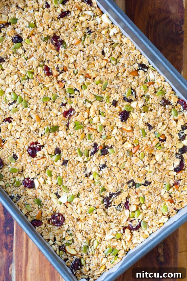 Granola bar mixture spread in a flat layer on a baking sheet.