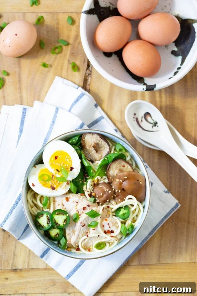 An overhead shot of two bowls of Slow Cooker Chicken Ramen Noodles, ready to be served, garnished with fresh ingredients.