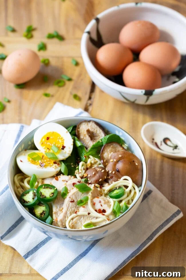 A close-up of an amazing ramen bowl filled with rich broth, noodles, chicken, mushrooms, fresh spinach, and a perfectly cooked soft-boiled egg, artfully arranged with various toppings.