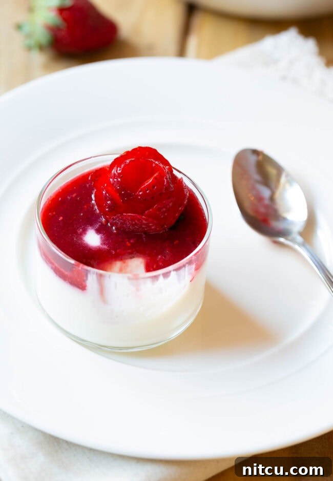 Small glass dish filled with silky white Swedish Cream, topped with a rich berry compote and a decorative strawberry rose.