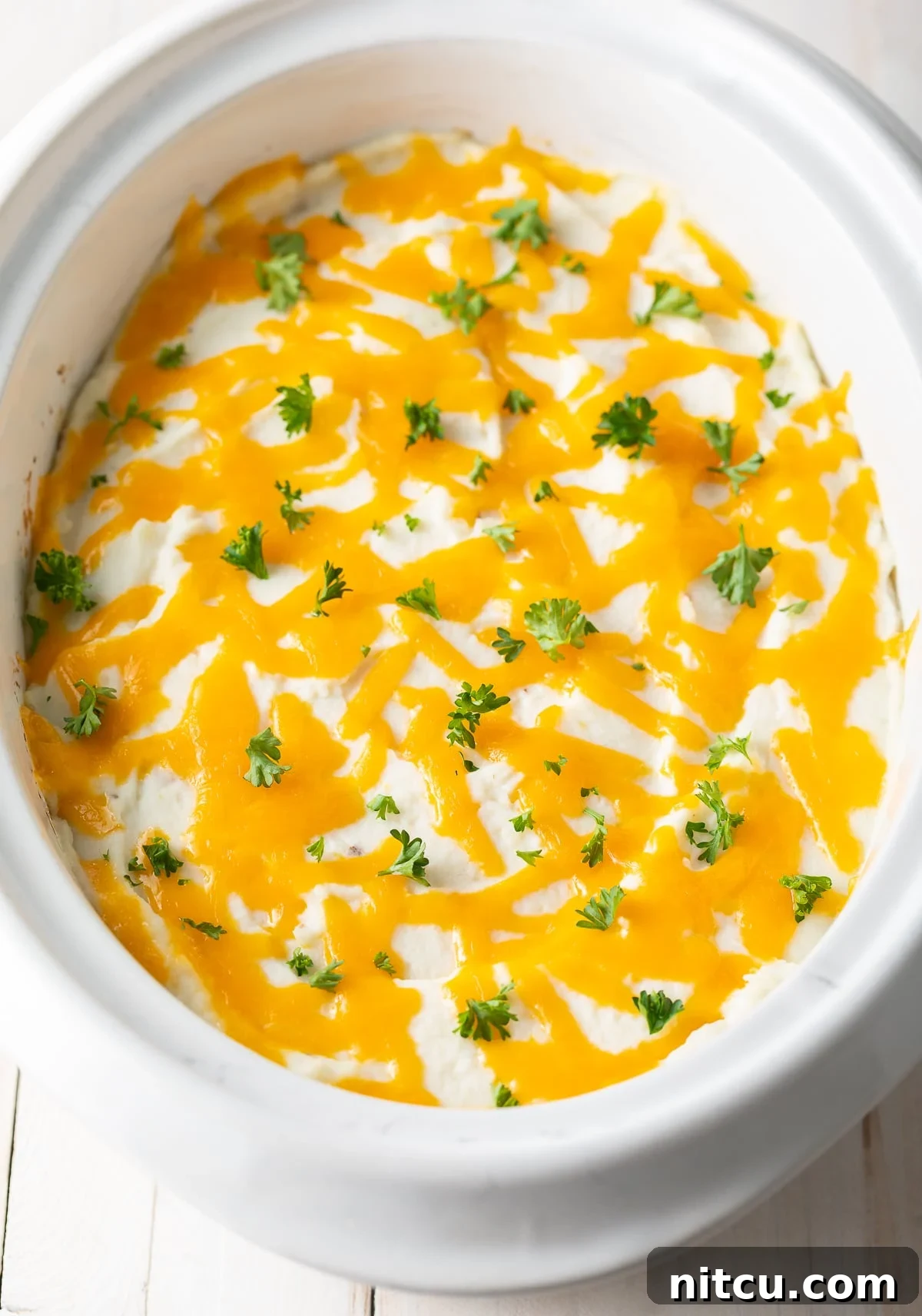 Overhead view of shepherd's pie in the crockpot with cheese and parsley on top. 
