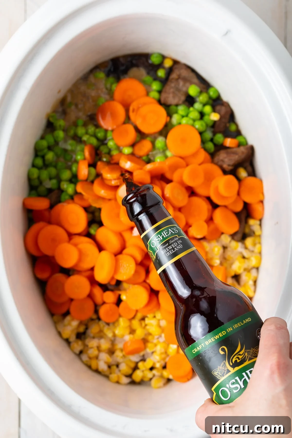 Pouring guinness on top of the vegetables and meat in a crock pot. 