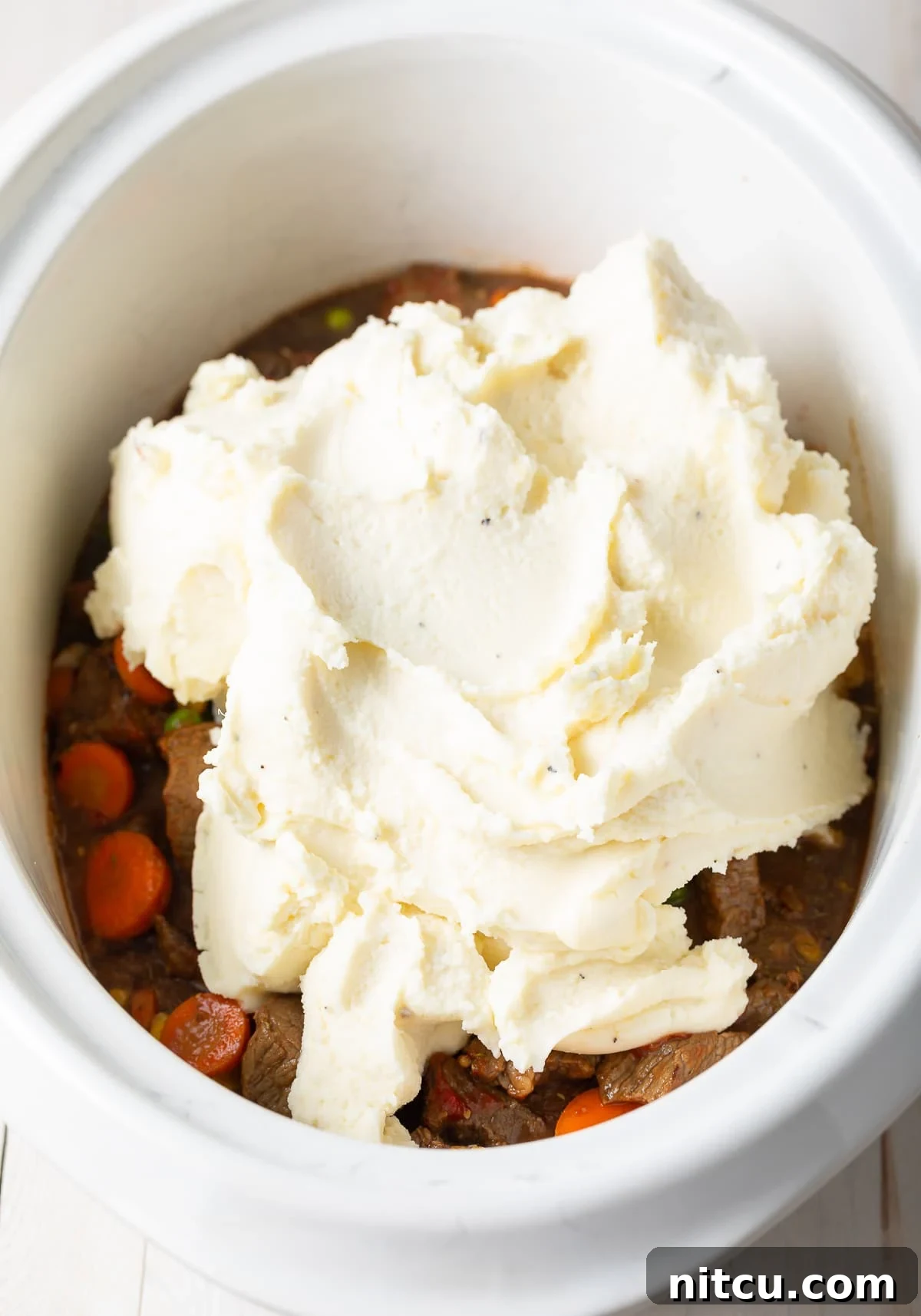 Mashed potatoes placed on top of the meat mixture in the crockpot. 
