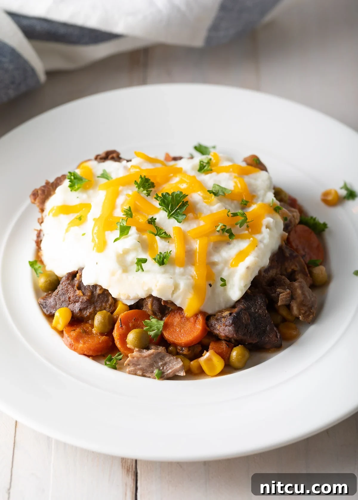 Shepherd's pie served on a plate with mashed potatoes on top. 