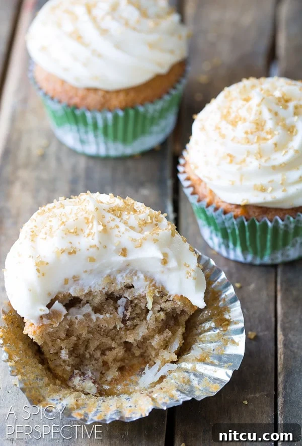 Close-up of a delicious Hummingbird cupcake with a bite taken, showing its rich texture. A delightful Hummingbird cupcake with a large bite taken out, revealing its moist interior packed with fruit and nuts.