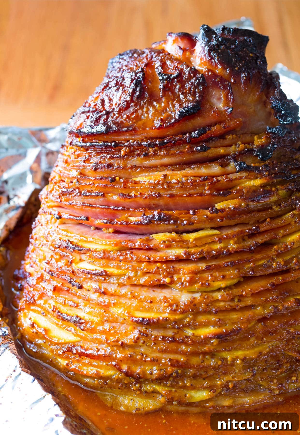 Honey-Glazed Ham with Roasted Apples 3 A close-up shot of the baked ham with apples nestled in a baking tray, showing the rich, golden-brown glaze and tender apple slices.