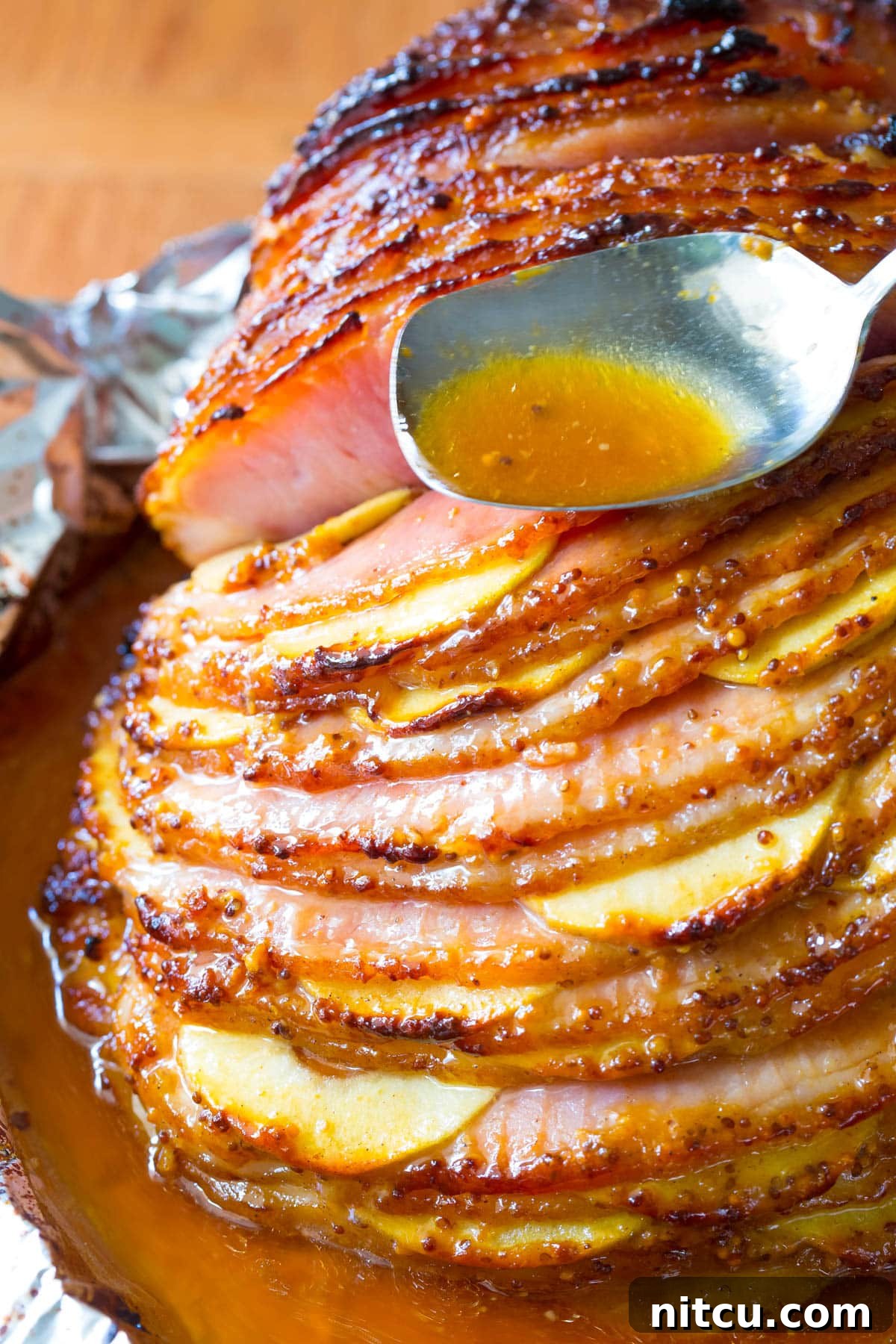 Honey-Glazed Ham with Roasted Apples 9 The fully baked honey mustard glazed ham, glistening and caramelized, nestled among softened apple slices in the baking dish.