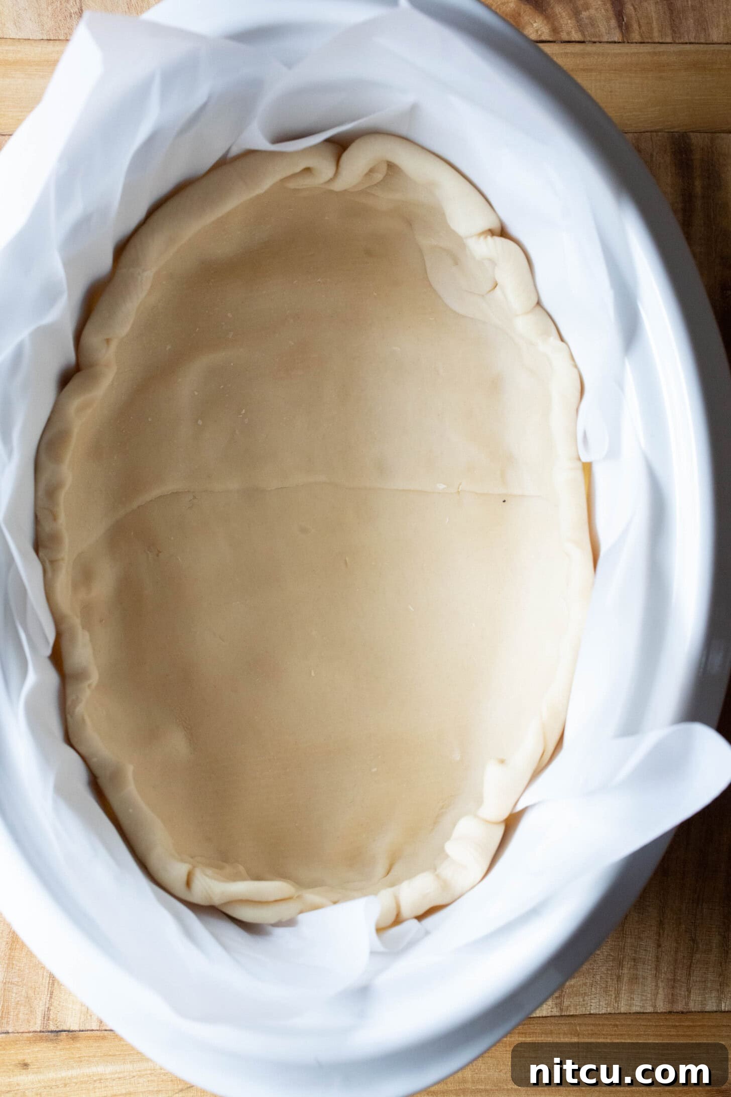 Top down shot of pie dough spread into the crockpot.