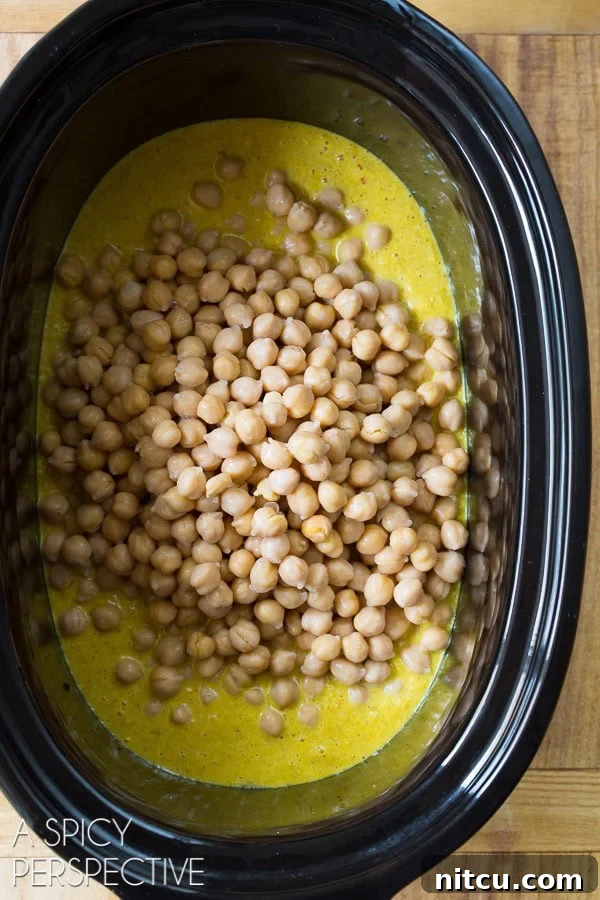 Crockpot filled with creamy curry sauce and chickpeas, before adding sweet potatoes.