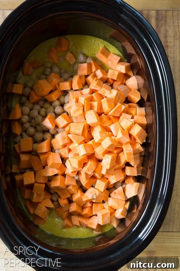 Crockpot with chopped sweet potato added to the curry and chickpeas, ready for slow cooking.