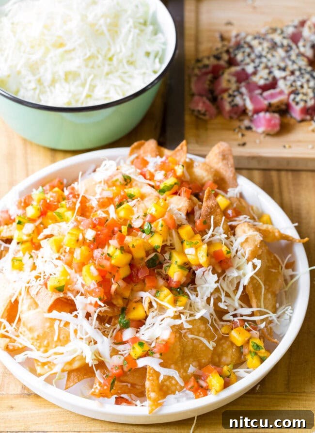 Aloha Ahi Poke Nachos 11 Crispy wonton chips on a white plate loaded with shredded cabbage and mango pico de gallo.