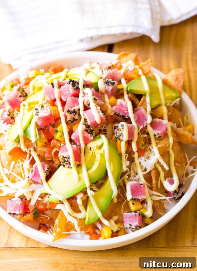 Aloha Ahi Poke Nachos 12 White bowl loaded with crispy wonton chips, cubes of seared ahi tuna, mango pico de gallo, shredded cabbage, avocado slices, and a drizzle of wasabi mayo.