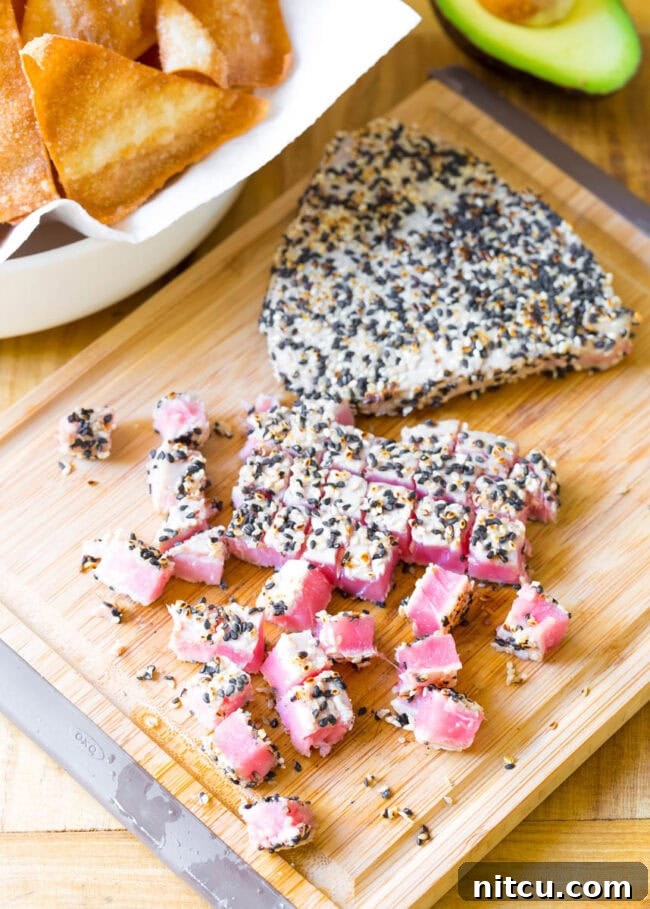 Aloha Ahi Poke Nachos 9 Two seared tuna steaks on a cutting board, one cut into cubes.
