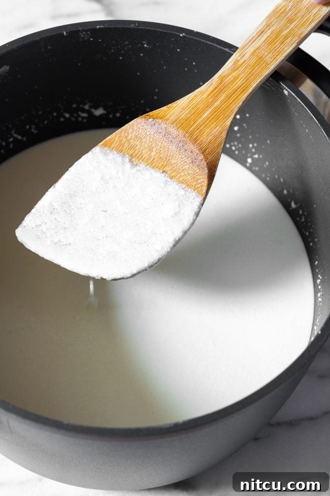 Crafting Creamy Ricotta at Home 6 Stirring the milk and cream mixture gently with a wooden spoon in a metal pot over heat, ensuring even heating.