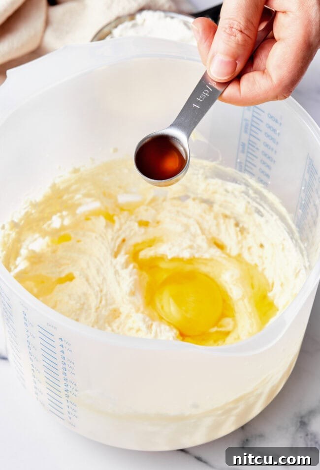 Tropical Sunrise Muffins 3 A hand adding vanilla to a mixing bowl with muffin batter.