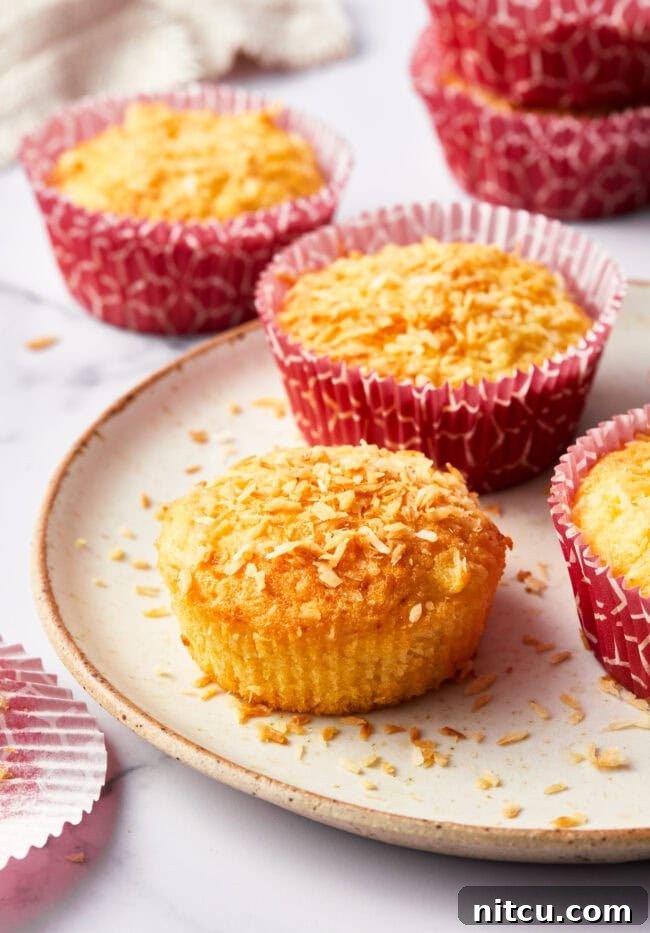 Tropical Sunrise Muffins 10 Tropical breakfast muffins on a white plate. The front muffin has the wrapper taken off.