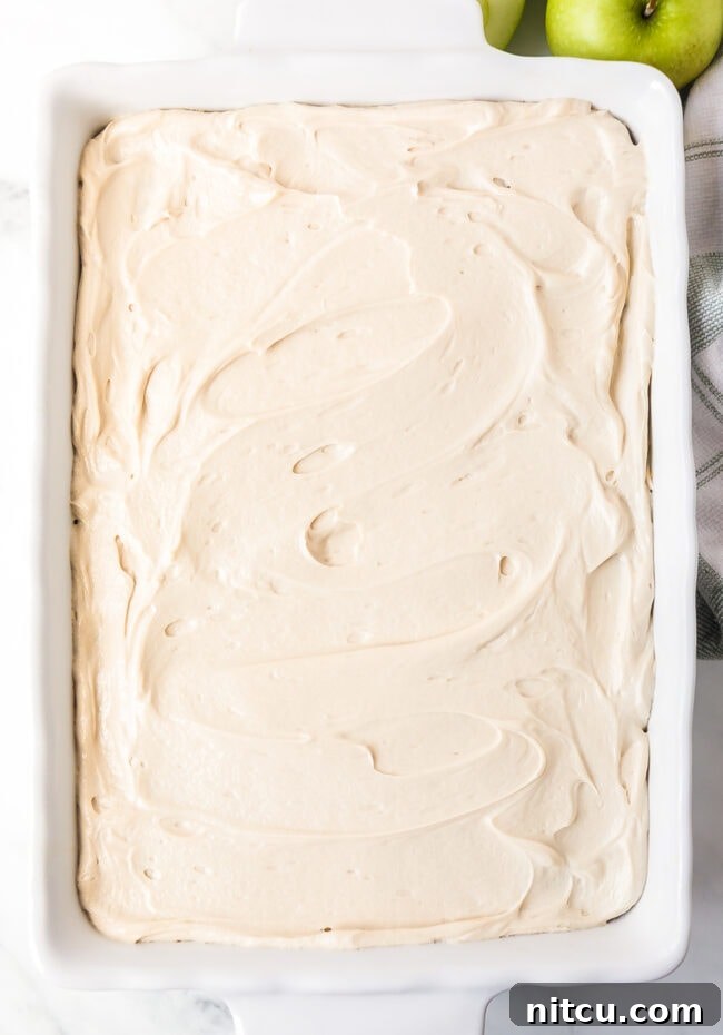 A beautifully frosted apple cake still in its baking pan, showing off its rich caramel topping.