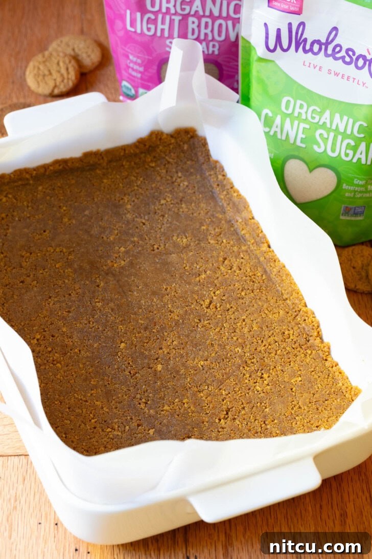 Spiced Pumpkin Cheesecake Squares 5 Smooth cheesecake batter being spread evenly over the gingersnap crust.