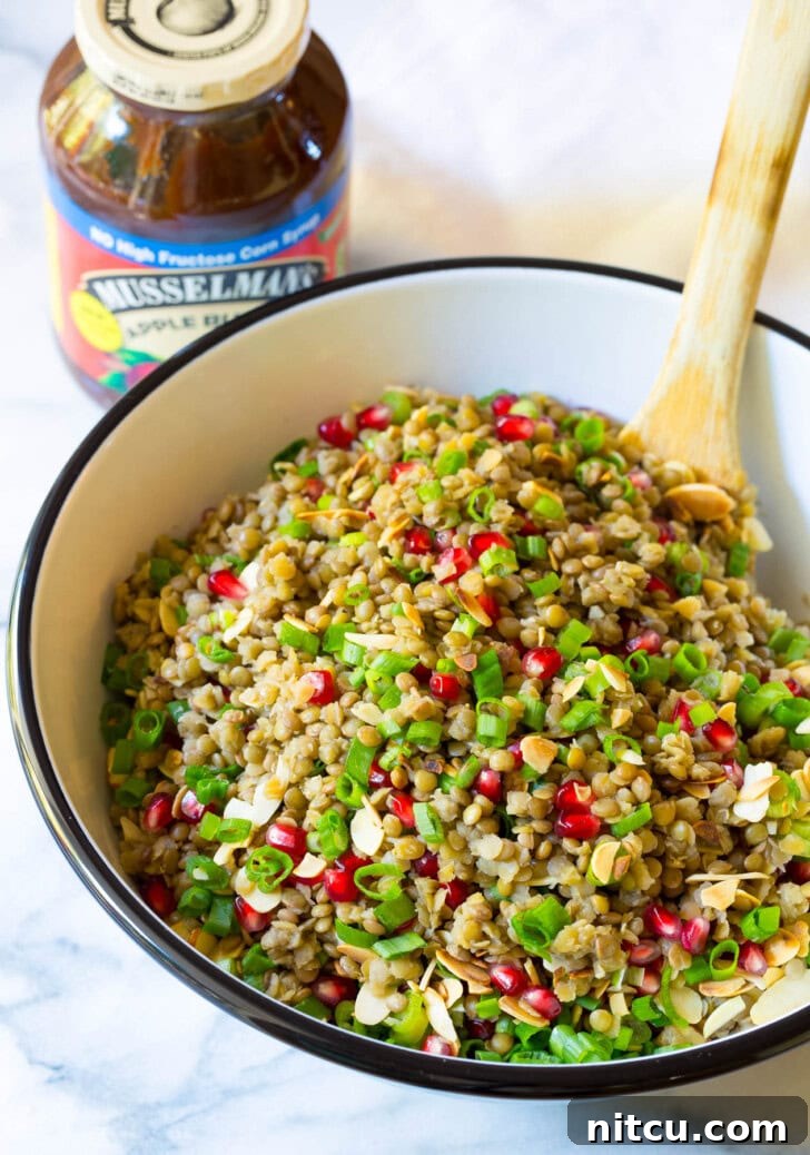 Wholesome Lentil Salad with Tangy Apple Dressing 7 Healthy Lentil Salad with Apple Cider Vinaigrette in a large serving bowl with a wooden spoon.