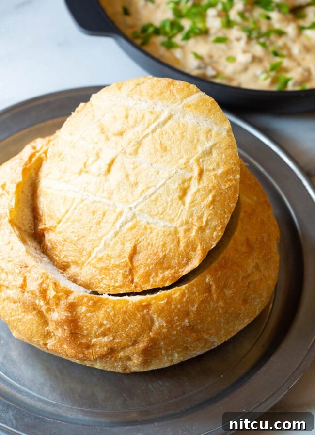 Velvety Sausage Cheese Dip 3 A large, perfectly prepared sourdough bread loaf with its top removed, revealing the hollowed-out center, ready to be filled with the delicious dip.