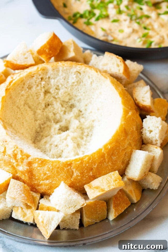 Velvety Sausage Cheese Dip 4 A rustic, hollowed-out sourdough bread loaf, perfectly prepared as a bowl, resting on a wooden surface before being filled with dip.