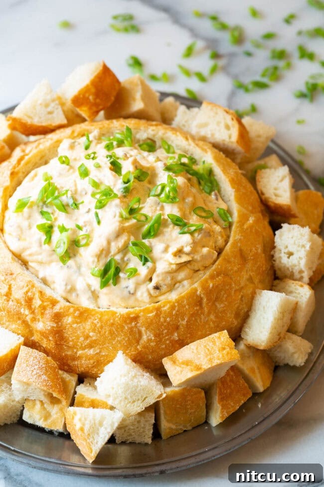Velvety Sausage Cheese Dip 8 Another inviting image of the creamy sausage cheese dip served in a sourdough bread bowl, artfully arranged on a platter with various dippers, ready for a festive gathering.