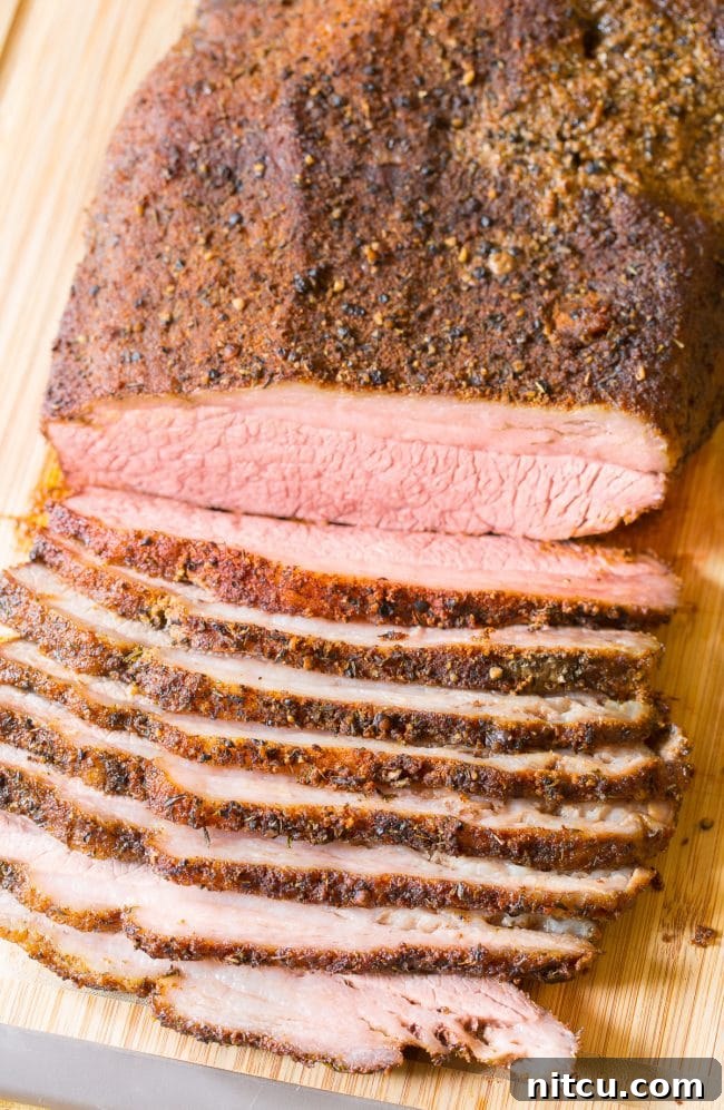 Close Up of Smoked Brisket #ASpicyPerspective #Brisket #BeefBrisket #BrisketRecipe #BeefBrisketRecipe #BrisektInOven #HowtoCookBrisket #TexasStyleBrisket #LiquidSmoke #SmokedBrisketRecipe #BrisketRecipeOven Sliced beef brisket (oven recipe) on a wooden cutting board.