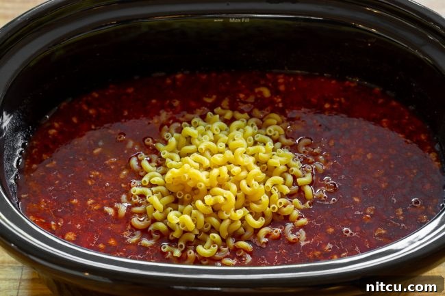 A colorful array of chopped red onion, red bell pepper, and minced garlic, essential fresh ingredients for the slow cooker chili mac and cheese recipe.