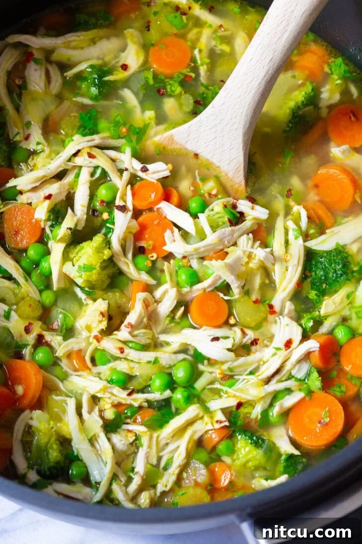 A close-up view of vibrant chicken vegetable soup simmering gently in a large pot, highlighting the fresh textures and colors of the healthy ingredients.