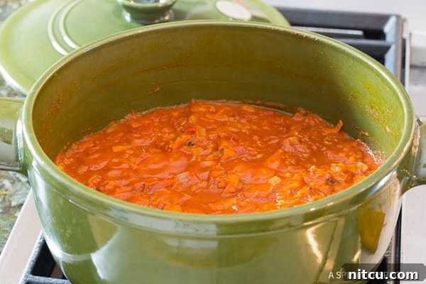 A green cooking pot with vibrant tomato sauce gently simmering, infused with fresh herbs.