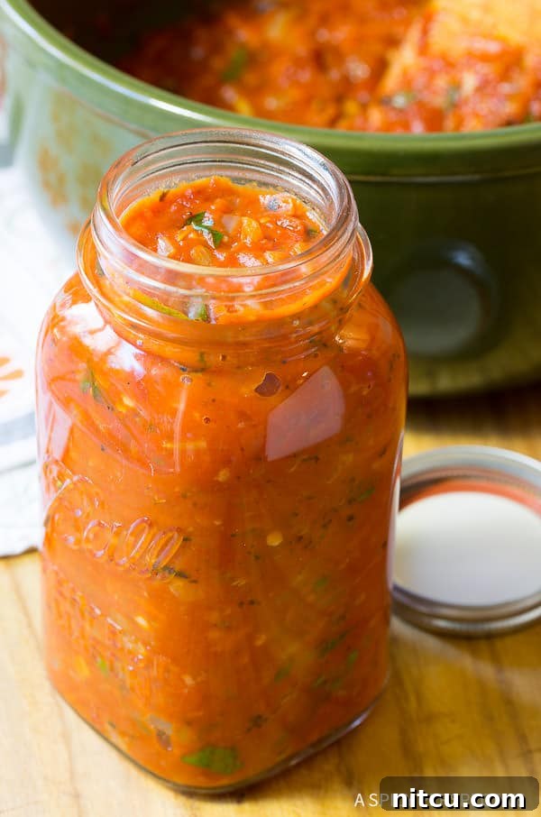A charming mason jar filled with savory homemade zesty marinara tomato sauce, resting on a wooden surface.